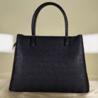Black embossed top handle satchel handbag with detachable shoulder strap and floral charm for women.