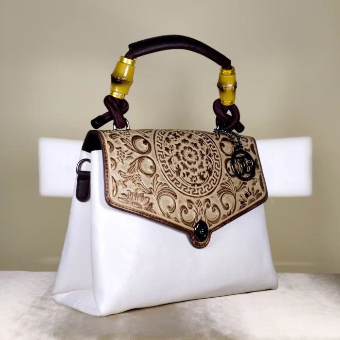 Ivory embossed top handle satchel bag with handle, a floral flap design, and detachable printed shoulder strap.