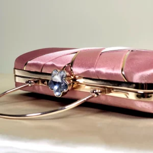 IMG_20260820_145215 A sophisticated structured clutch bag featuring an elegant rectangular silhouette, decorative overlapping front detailing, and a sleek top handle. Perfect for adding a refined touch to evening and special-occasion outfits.
