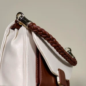 Ivory and brown structured flap top handle sling bag with braided handle and adjustable shoulder strap